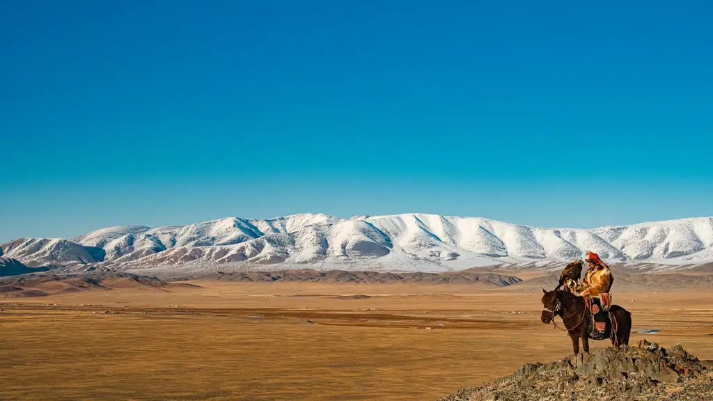 A hunter on horseback looks out at the snow-covered Altai