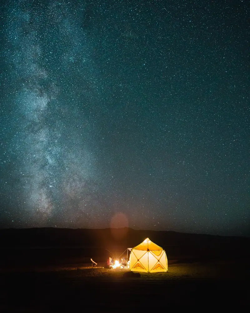 A lit tent under the Milky Way