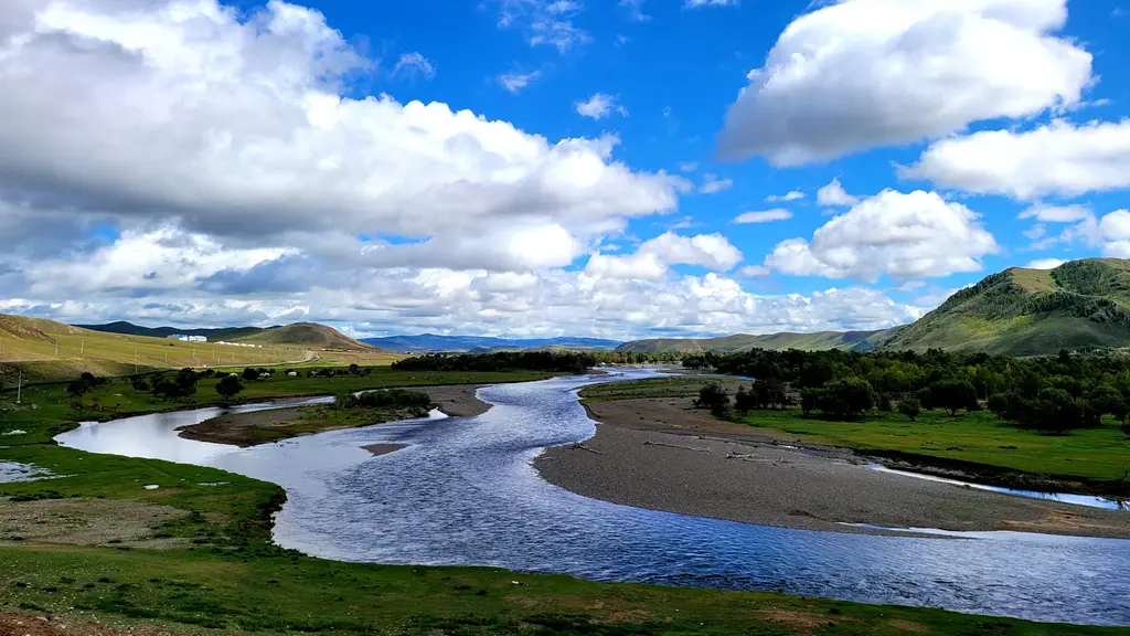 A river winding through a green valley under big clouds
